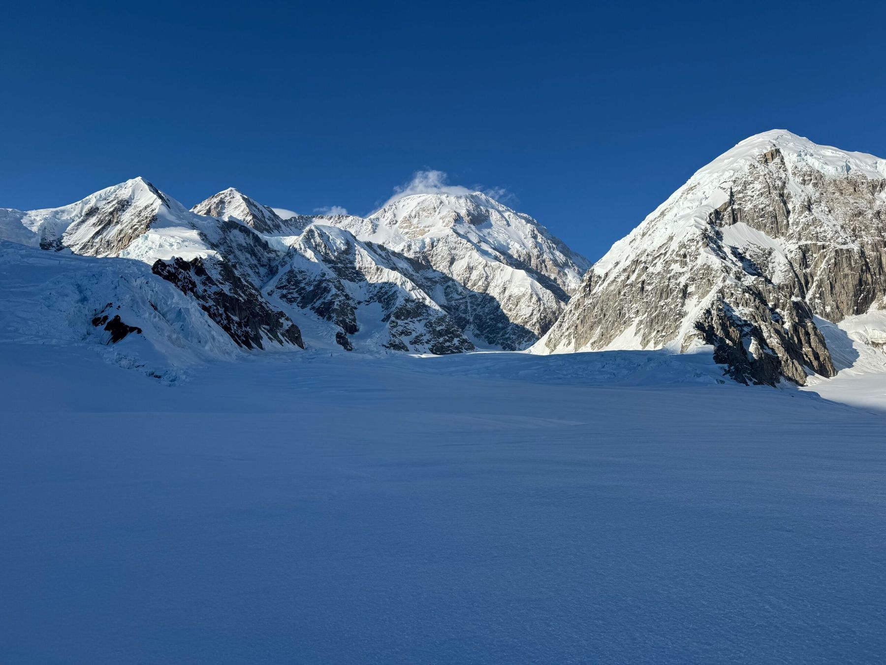 Snow covered peaks above a glacier under a blue sky